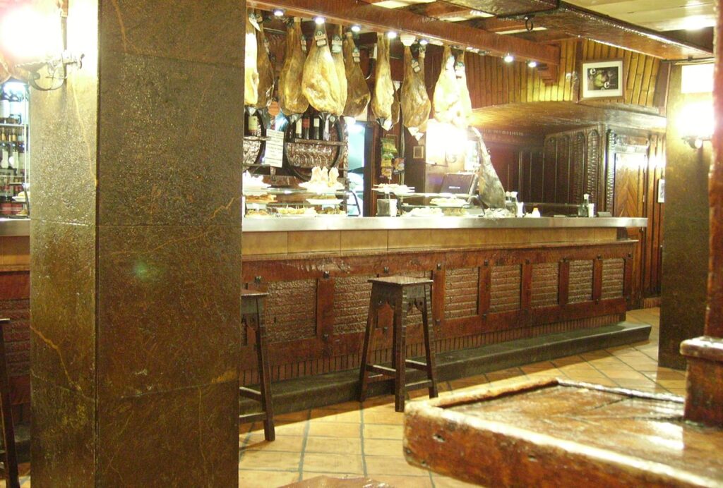 Fotografía antoigua del interior del Bodegón Sarría, con sus típicos jamones.